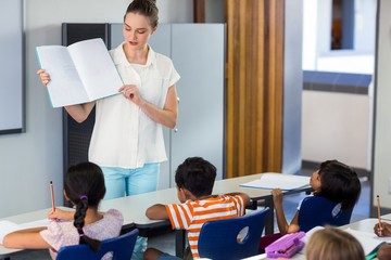 Teacher showing book to schoolchildren