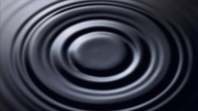 Overhead view of ultra-slow motion drop falling onto dark water and creating ring of ripples