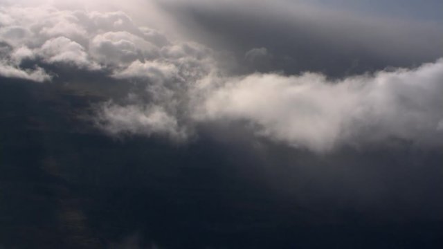 Tilting flight through wispy clouds at edge of gray cloud mass
