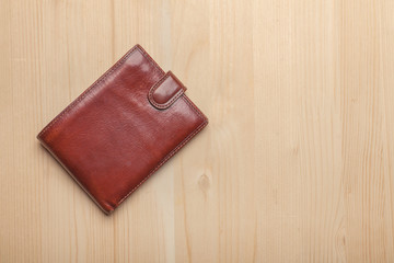 brown leather wallet on wooden table, top view