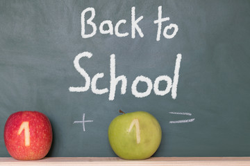 eine Tafel mit einem Text zur Einschulung und zwei Äpfel