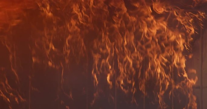 Flickering flames crawl up the walls and roll beneath the ceiling of a burning structure