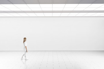 Empty big hall wall mockup. Woman walk in museum gallery with blank wall. White clear stand mock up...