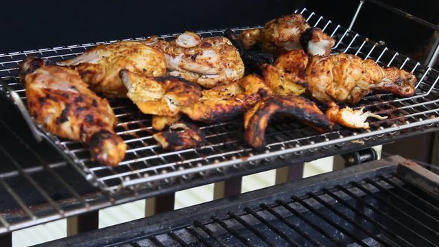 Grilled Tandoori Chicken marinated with yogurt, garlic, ginger, and exotic spices cooking on a barbecue grill.