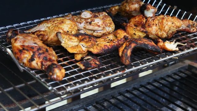 Grilled Tandoori Chicken marinated with yogurt, garlic, ginger, and exotic spices cooking on a barbecue grill.