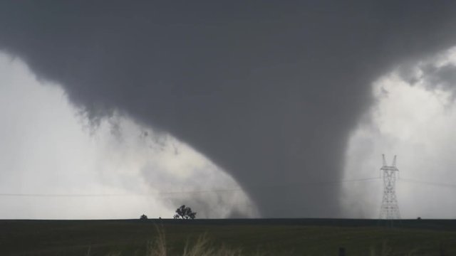 A massive wedge-shaped tornado looms above Nebraska farmland