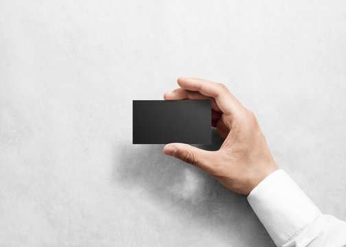 Hand hold blank plain black business card design mockup. Clear namecard mock up template holding arm. Visit pasteboard paper surface display front. Check small offset card print. Business branding