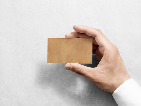 Hand hold blank plain kraft business card design mockup. Clear calling card mock up template holding arm. Visit pasteboard craft paper display front. Small offset texture card print. Business identity