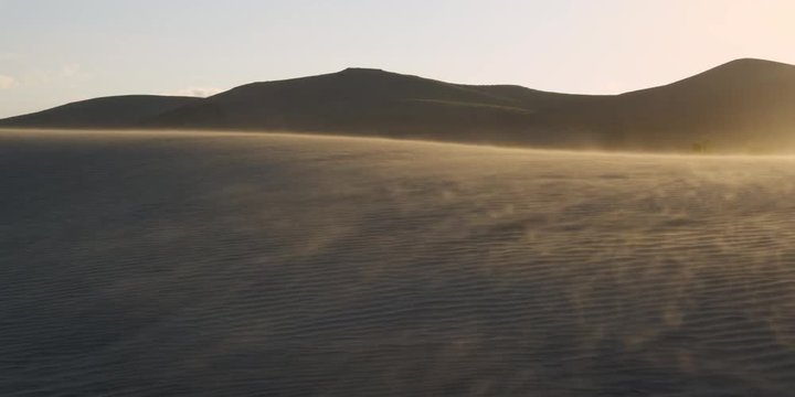 Afternoon light on sand blowing across desert dunes