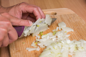 Frau schneidet Zwiebel zu Würfel als gewürfelte Zwiebeln auch Zwiebelwürfel
