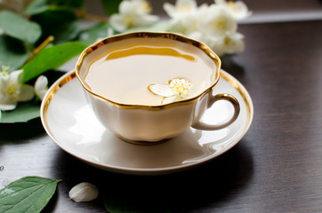 Jasmine tea in a porcelain Cup on a dark wood