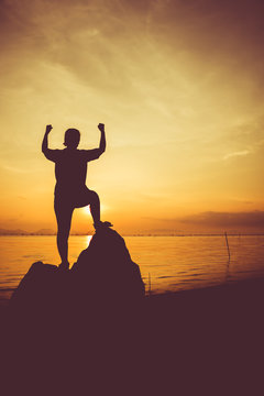 Silhouette of successful woman relax and showing arm up gesture. Action of winner. Vignette and vintage picture style.