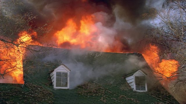 Flames rising from behind roof of burning house