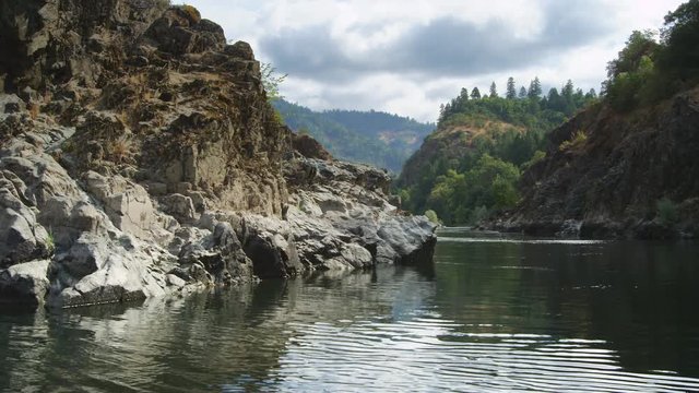 Drifting between canyon walls on a placid stretch of the Rogue River, Oregon; looking back upstream