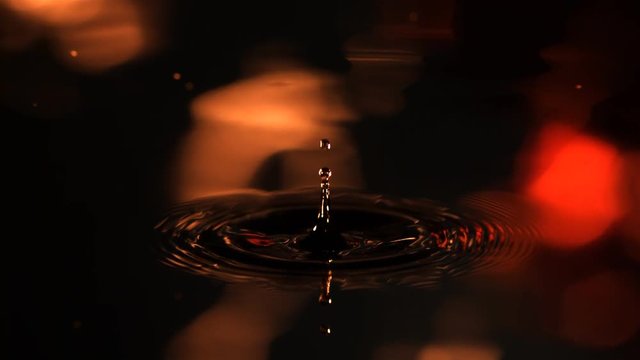 Ultra-slow motion drop falling and spreading ripples over amorphous reflections