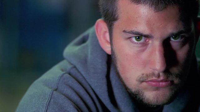 Close-up of an unsmiling young man in a gray sweatshirt