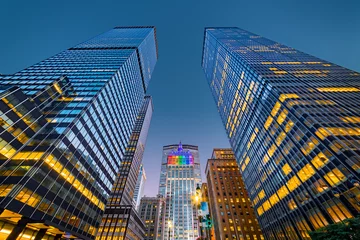 Poster Opwaartse weergave van New York wolkenkrabbers in de schemering. Het centrale gebouw, verlicht met regenboogkleuren, viert de Gay Pride-week © mandritoiu