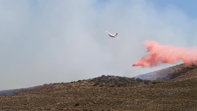 Firefighting plane drops a load of fire suppressant in the path of a wildfire