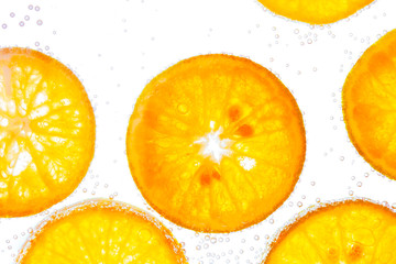 Fresh orange slice in water with bubbles on white background