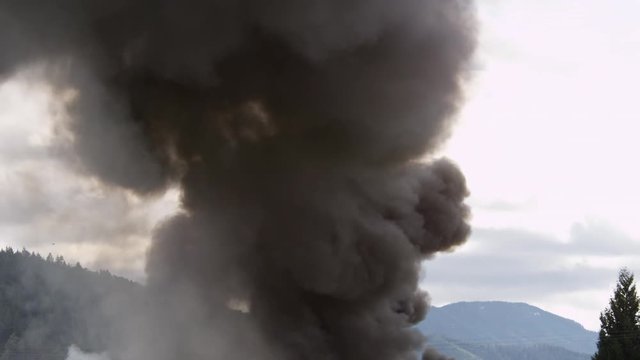 Clouds of thick black smoke rise above a burning structure