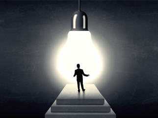 Man standing on a step in front of a huge light bulb