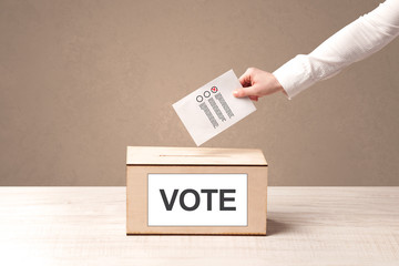 Close up of male hand putting vote into a ballot box