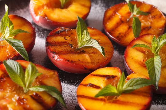 Grilled Peaches with powdered sugar and mint macro on a plate. Horizontal
