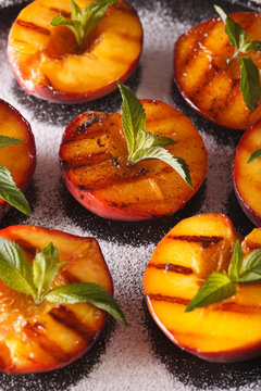 Grilled Peaches with powdered sugar and mint macro on a plate. Vertical
