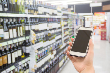 hand holding mobile phone on Supermarket blur background, business concept