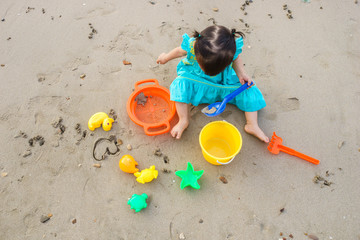Cute little girl building sandcastle on tropical summer beach