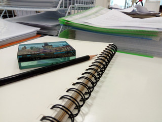 Black Pencil and Paperweight  on  open Note book