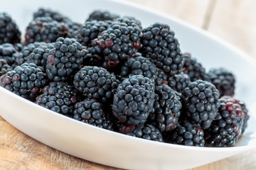 Fresh ripe blackberries in white bowl
