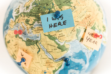 I was here - globe map with colorful pins and post-it notes marking travel destinations - close up. 