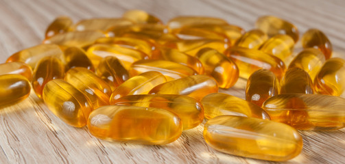 Omega3 fish oil capsules in shape on wooden background