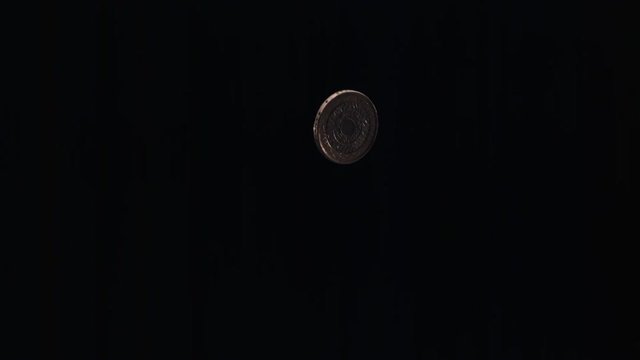 British coin flipping on black frame in ultra-slow motion