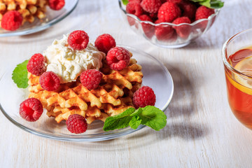Waffles garnished with mascarpone and raspberries.