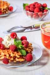 Waffles garnished with mascarpone and raspberries.