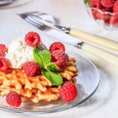 Waffles garnished with mascarpone and raspberries.