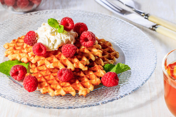 Waffles garnished with mascarpone and raspberries.