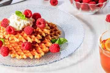 Waffles garnished with mascarpone and raspberries.
