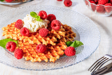 Waffles garnished with mascarpone and raspberries.