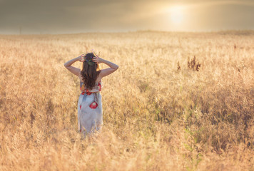 Portrait of a young woman in a wheat field, at sunset