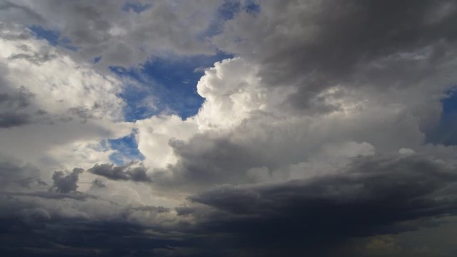 Dark gray time-lapse clouds pass in front of billowing cumulus