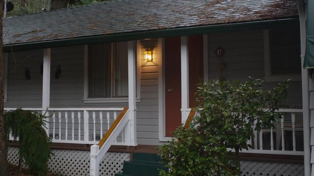 Zoom-in on motel cabin door beside a glowing porch light