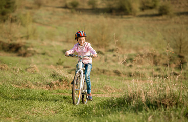 Fototapeta premium smiling little girl riding a bike in helmet 