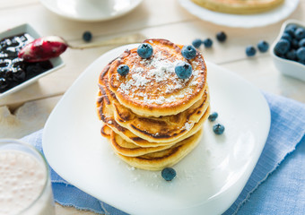 pancakes with blueberry and jam on white wooden table