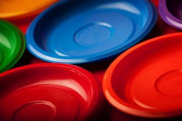 Colored plastic plates on red background