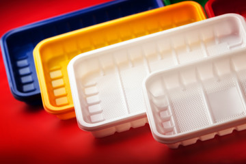 Colored plastic utensils on red background