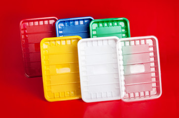 Colored plastic utensils on red background