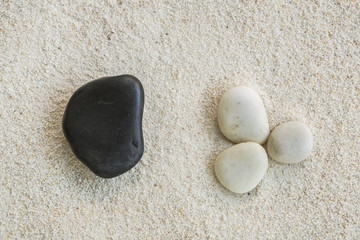Fototapeta na wymiar Black Stone and White stones in the sand, Balance concept